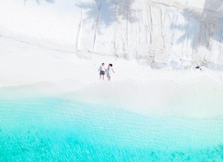 A couple walking on a white sandy beach with clear turquoise water. 4