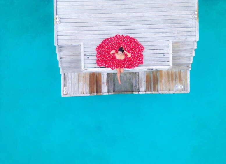 A person sitting on a wooden bench with a red floral dress. 2
