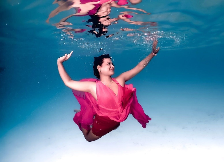 A person underwater in a pink dress. 1