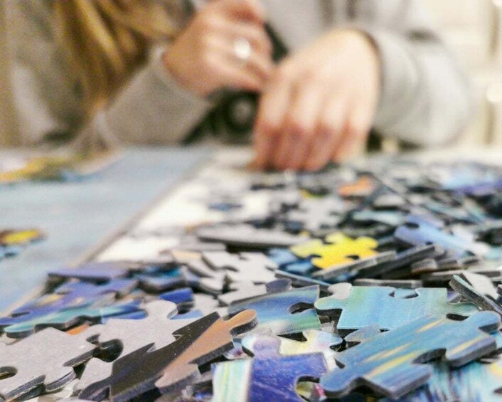 A person assembling a jigsaw puzzle with various colors and shapes. 3