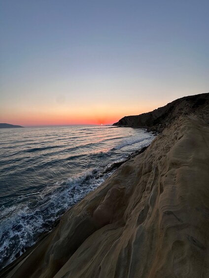 A coastal landscape with a sandy beach, waves, and a sunset. 4