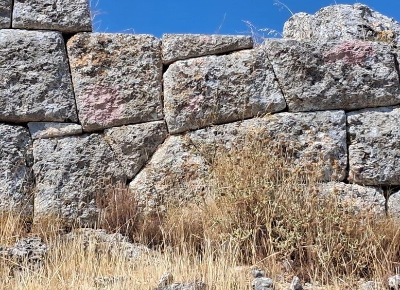 A stone wall with dry grass in front. 2