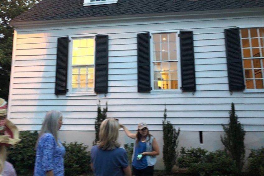 A house with white siding and black shutters, surrounded by greenery. 5