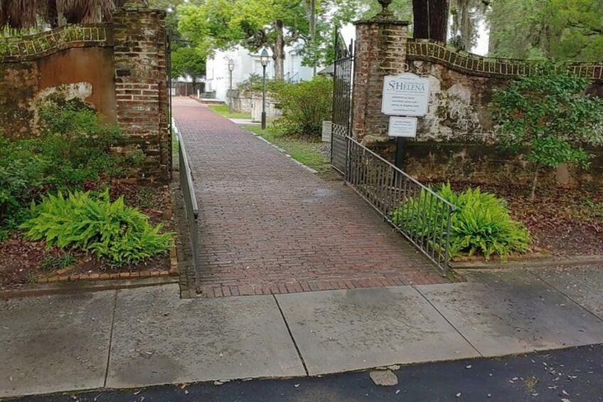 A brick pathway leading to a gated entrance with a sign reading 'Shetena.' 4
