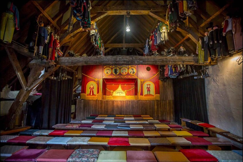 A wooden interior with a sloped ceiling, benches, and a wall with religious icons. 4