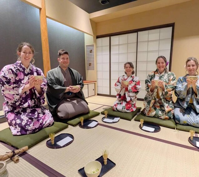 A group of people in traditional Japanese attire sitting on tatami mats in a room with shoji screens. 3