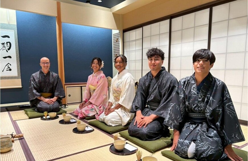 A group of people in traditional Japanese attire sitting on tatami mats in a room with shoji screens. 2