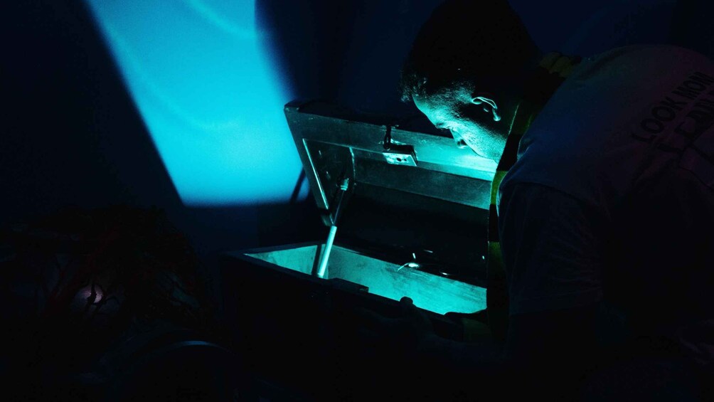 A person working with a computer in a dimly lit room. 3