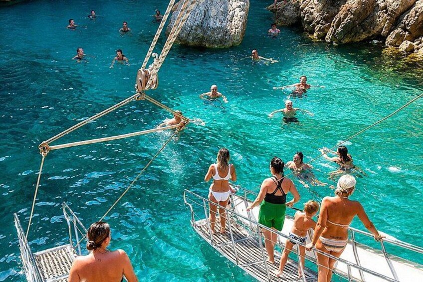 A group of people swimming in a clear blue pool surrounded by rocky cliffs. 2
