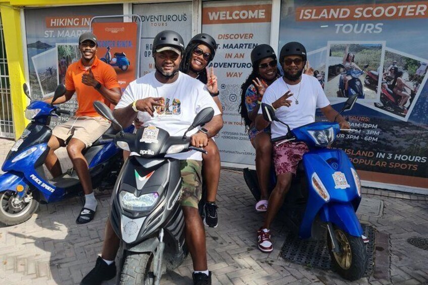 Four people on scooters in front of a sign for island scooter tours. 1