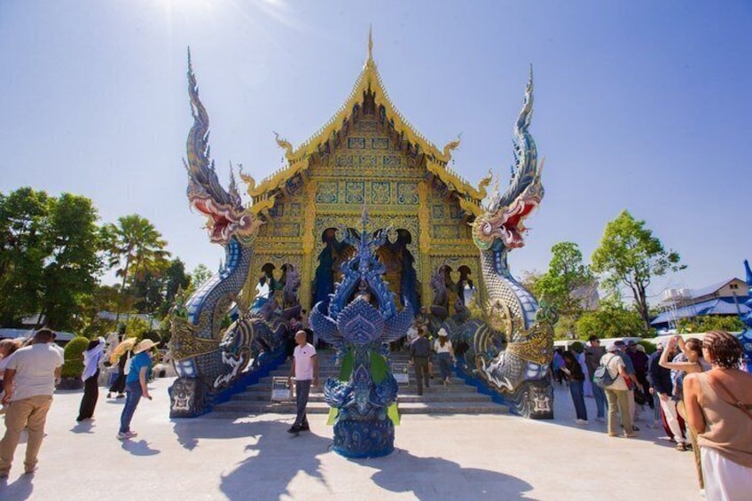 A temple with ornate blue and gold decorations and a dragon statue in front. 1