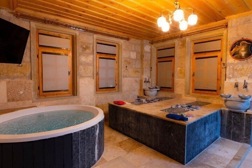 A bathroom with a stone wall, wooden ceiling, and a bathtub. 1