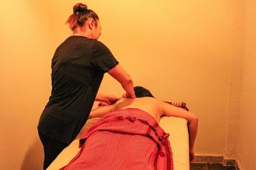 A person receiving a massage in a room with a plain wall and a wooden floor. 3