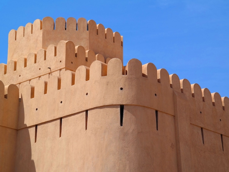 A large, beige-colored fortress with crenellated battlements and a prominent central tower. 1