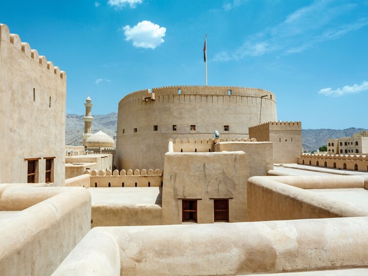 A fortress with a central tower and a flagpole, surrounded by walls and smaller buildings. 3