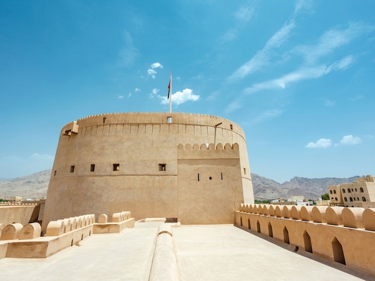 A large, round fortress-like structure with a flagpole, set against a mountainous backdrop. 4