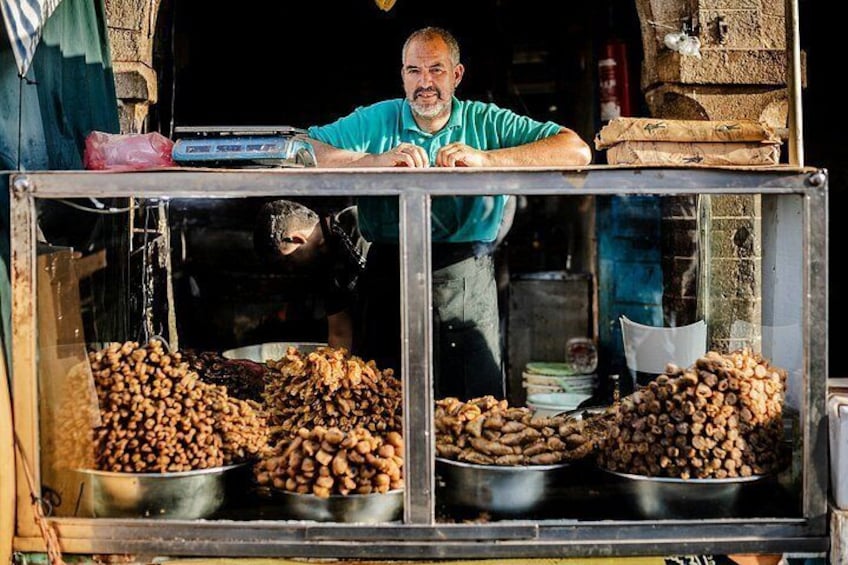 A street food vendor with a display of nuts and a weighing scale. 1