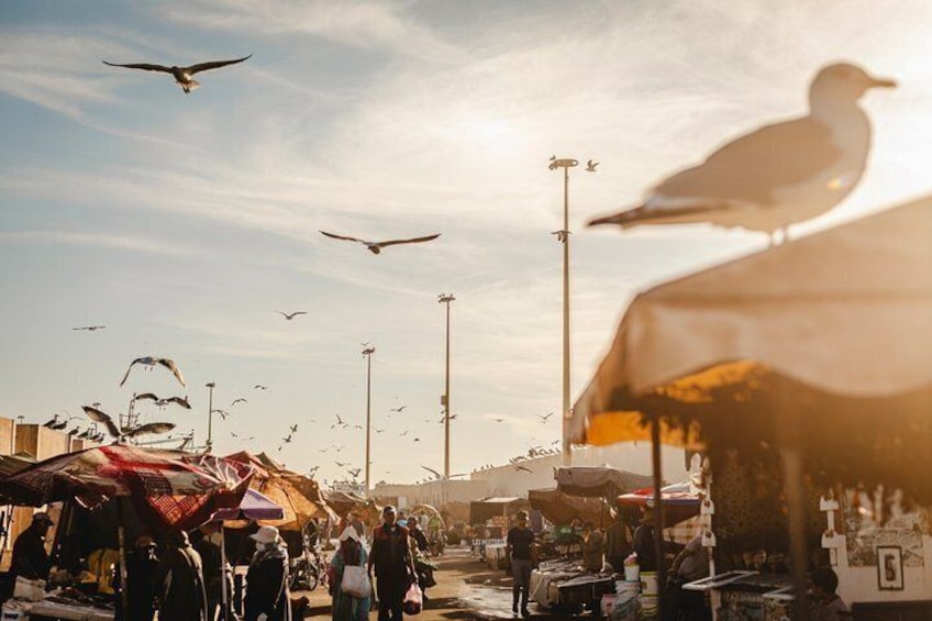 A bustling outdoor market with people and stalls under a clear sky. 1
