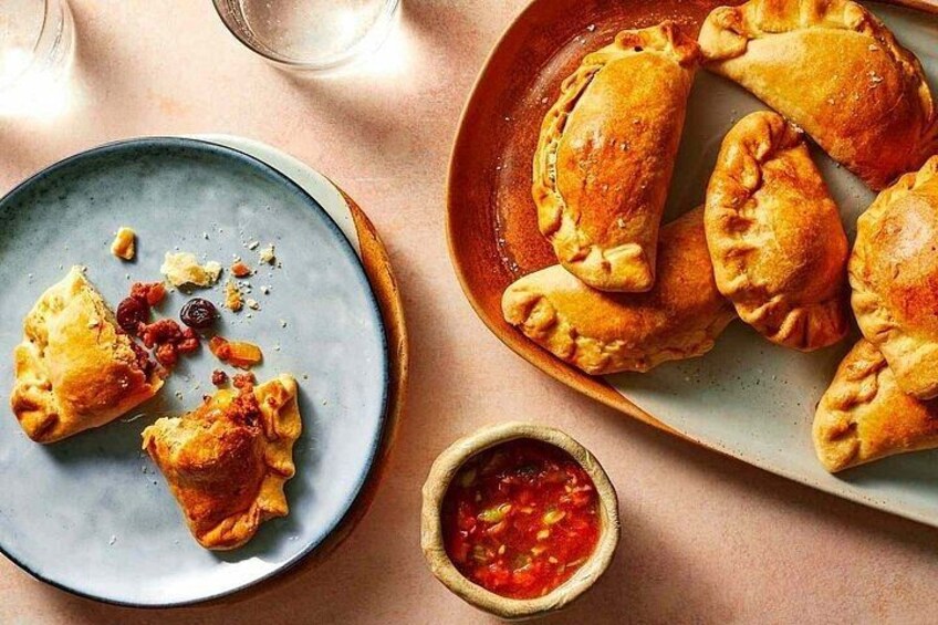 A plate of golden-brown pastries with a red sauce on the side. 3