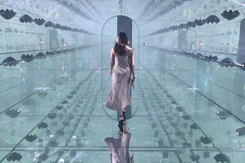 A woman walking through a mirrored hallway with heart-shaped decorations. 3