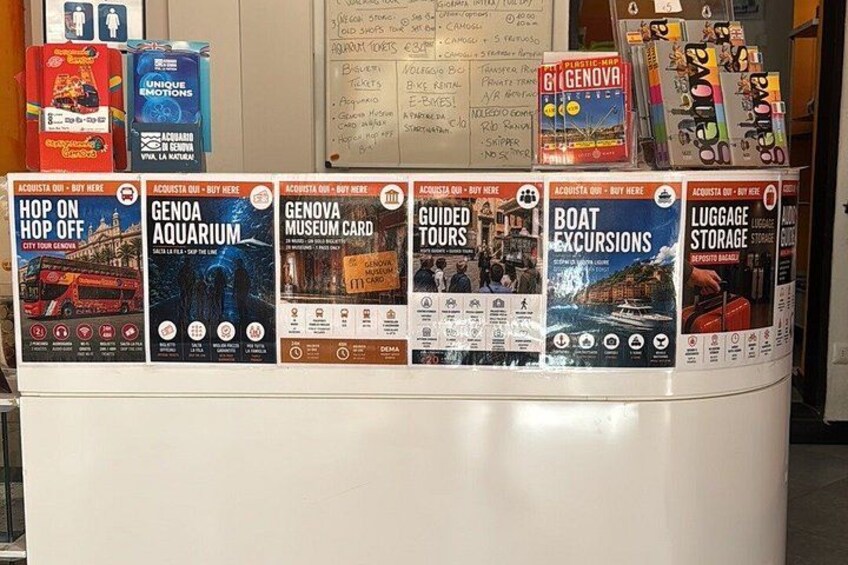 A display of travel brochures for Genoa, including attractions like the Aquarium, museum card, guided tours, boat excursions, and luggage storage. 4