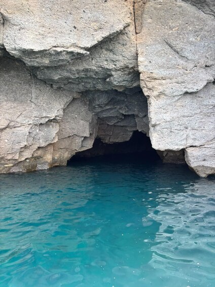 A natural rock formation with a cave entrance and clear blue water. 2