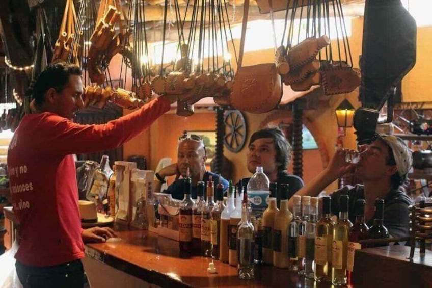 A person serving drinks at a bar with various bottles and glasses on the counter. 3