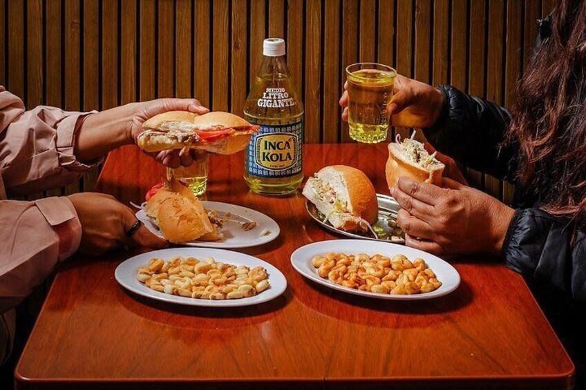A wooden table with plates of food, a bottle of drink, and a glass. 3