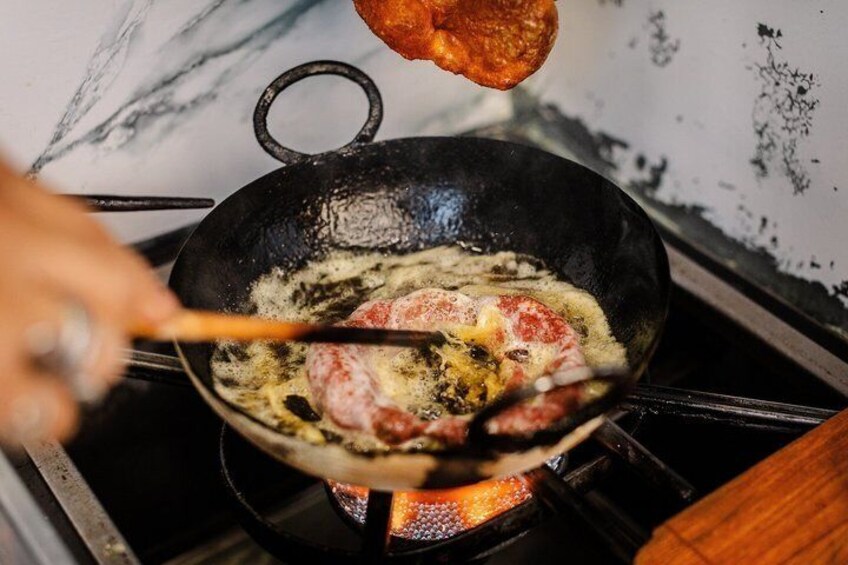 A frying pan on a stove with food being cooked. 1