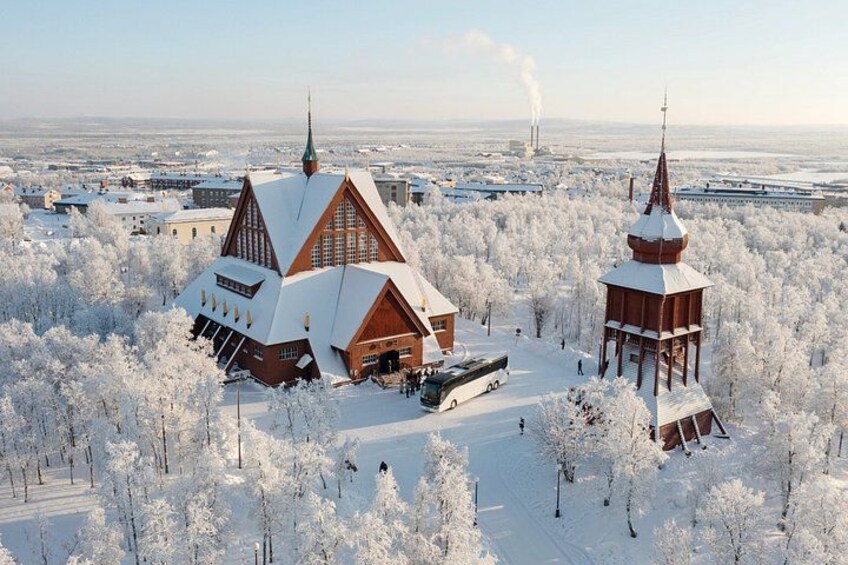 A wooden church with a steep roof and a bell tower, surrounded by snow-covered trees. 4