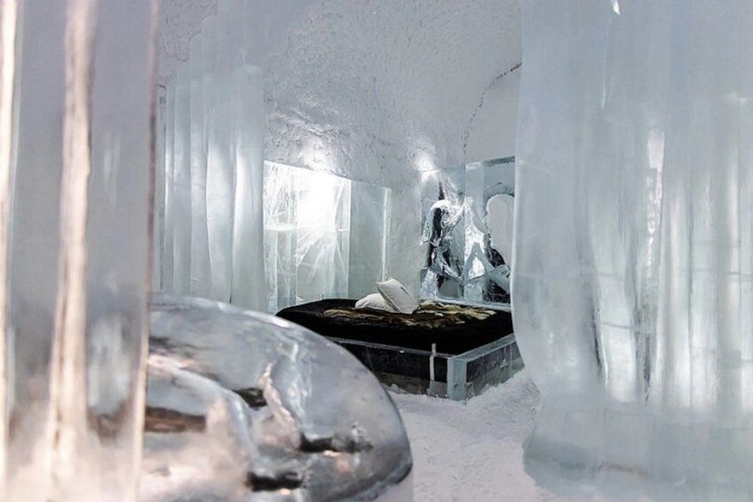 An ice hotel room with a bed and a window. 5