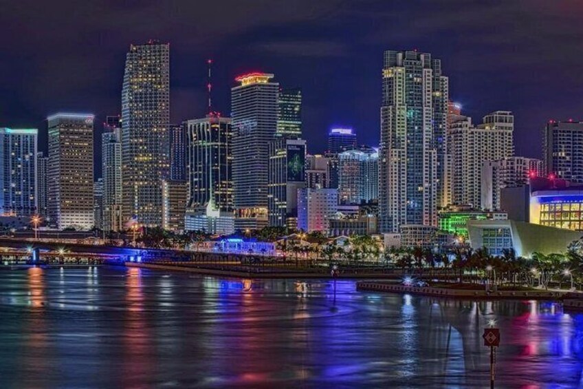 A city skyline at night with illuminated buildings reflecting on the water. 3
