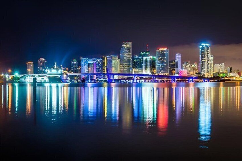 A city skyline at night with illuminated buildings reflecting on the water. 5