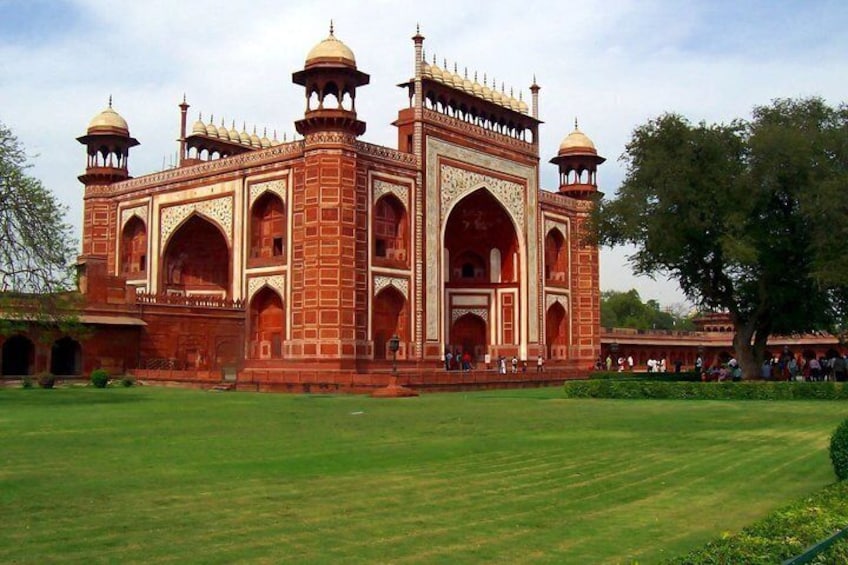 A large, historic building with multiple domes and arches, surrounded by a well-maintained lawn. 2