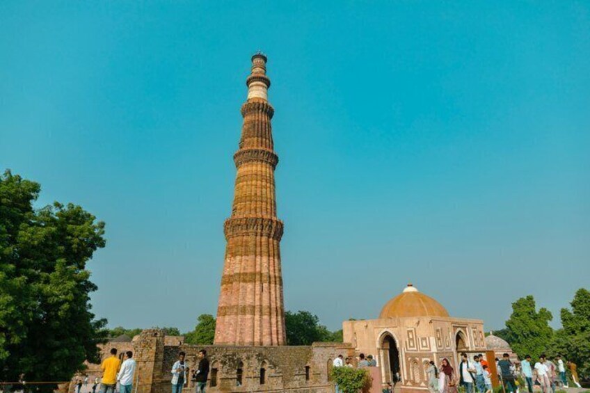 A tall, historic tower with a dome, surrounded by trees and a crowd of people. 3