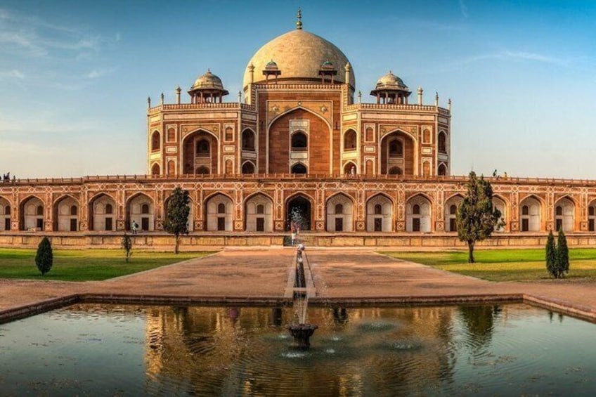 A large, historic building with a central dome and arched windows, surrounded by a reflective water body and greenery. 5