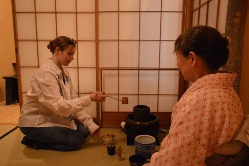 Two people sitting on tatami mats in a traditional Japanese room with sliding doors. 1