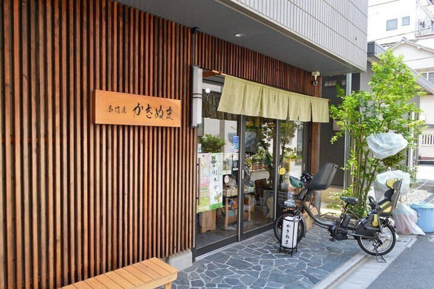 A wooden building with a sign, a bicycle, and a small tree. 3