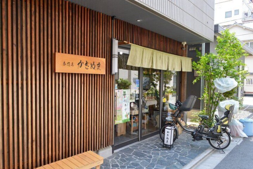 A wooden exterior wall, a sign with Japanese characters, a bicycle, and a covered entrance. 3