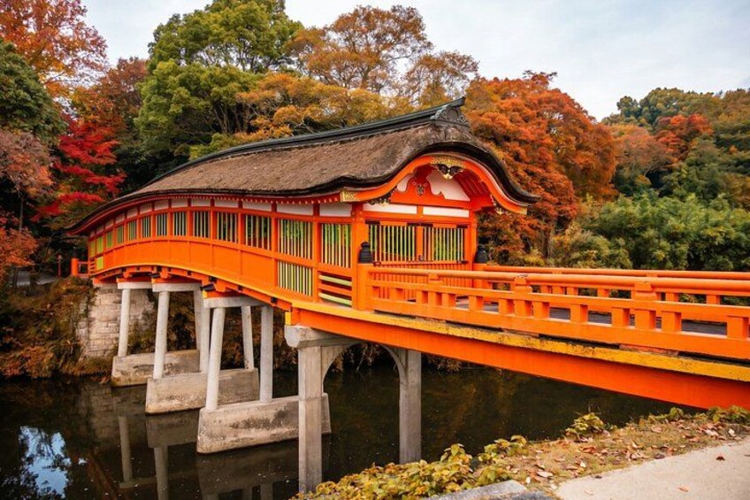 A traditional Japanese bridge with a thatched roof, vibrant orange railings, and a stone base. 2