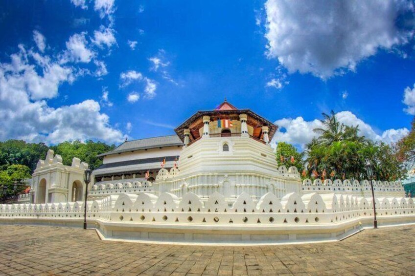 A large white temple with a red roof, surrounded by a white fence and palm trees. 3