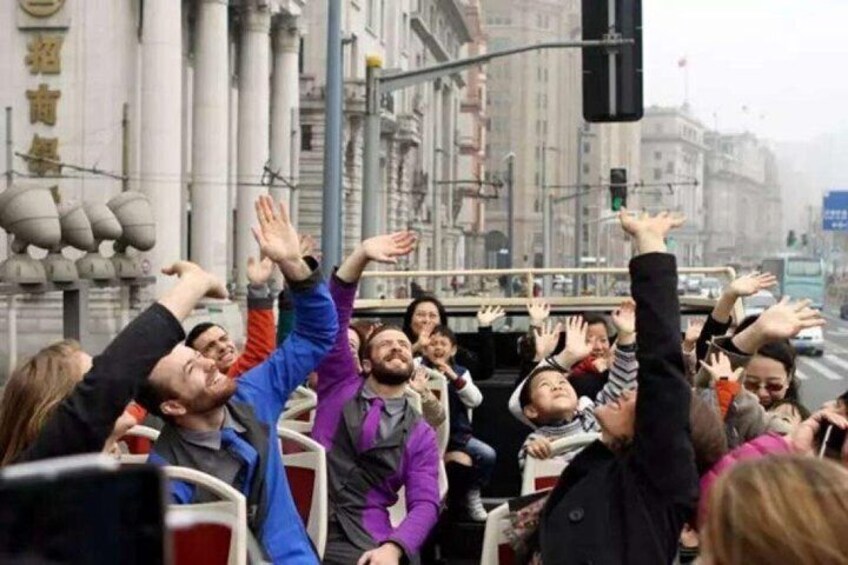 A crowd of people with raised hands, some wearing jackets, in an urban setting with buildings and a traffic light. 1