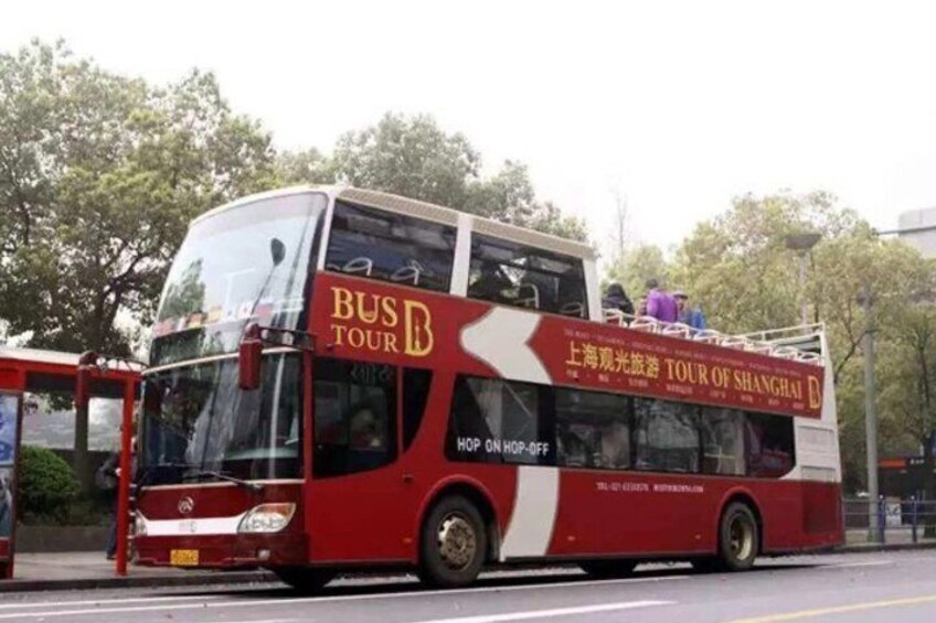 A red double-decker bus with 'BUS TOUR' and 'TOUR OF SHANGHAI' written on it. 2