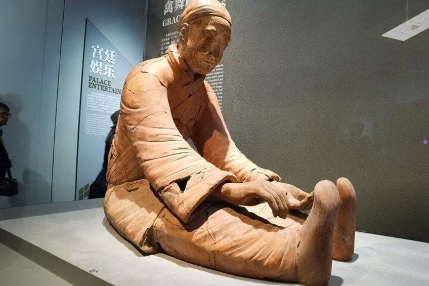 A seated terracotta statue in a museum setting. 5