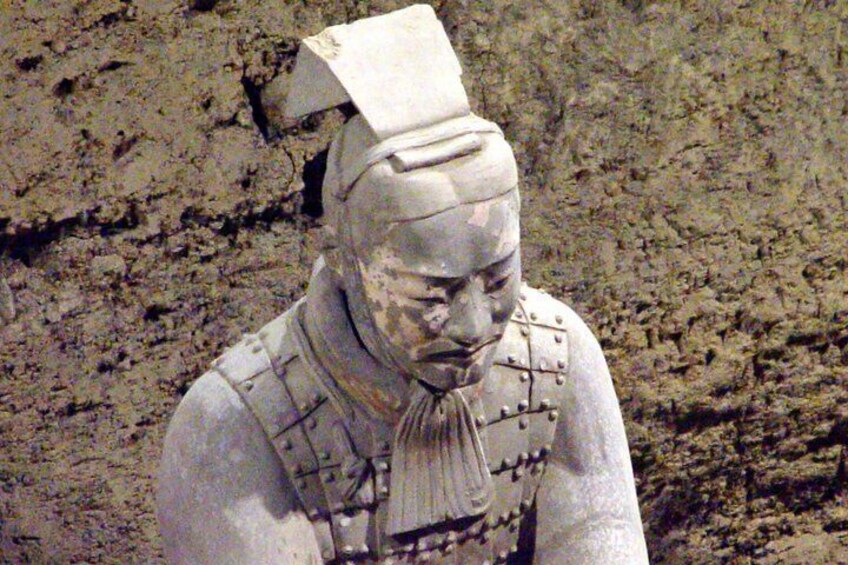 A terracotta statue of a warrior with a helmet, armor, and a scroll. 4