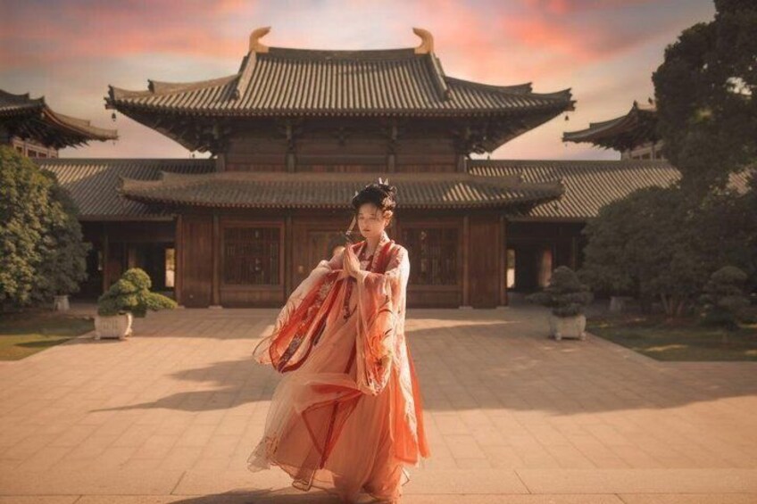 A person in traditional attire in front of a classical building with a tiled roof. 1