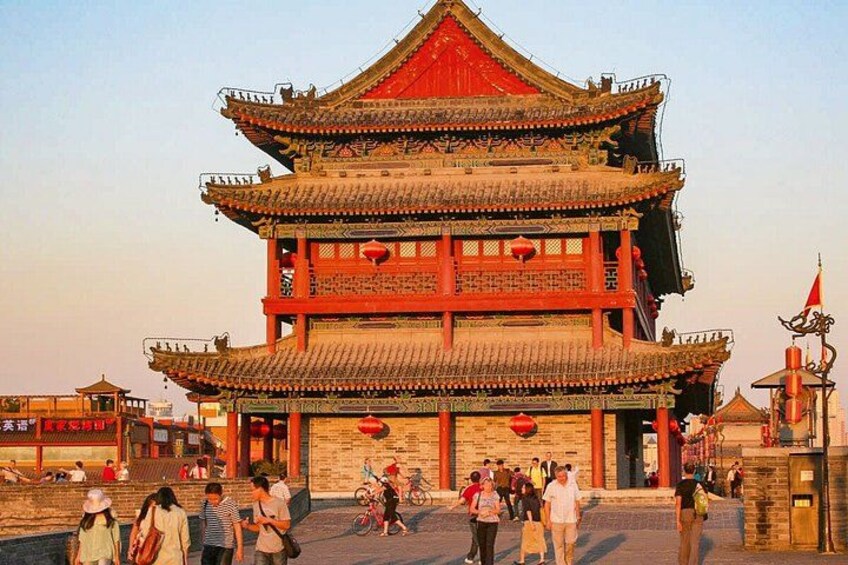 A traditional multi-tiered building with red and gold accents, surrounded by people and bicycles. 2
