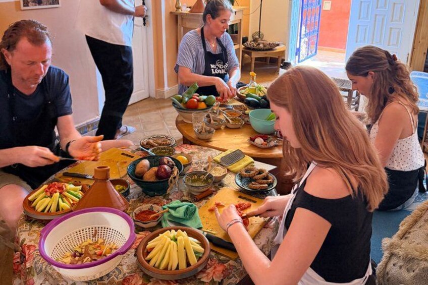 A group of people preparing food at a table with various ingredients and utensils. 5