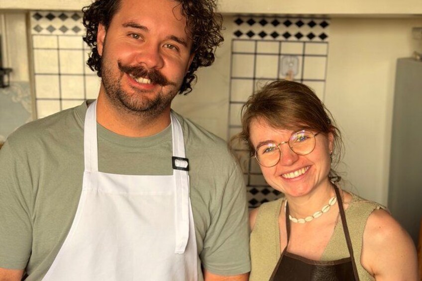 Two people in a kitchen, one wearing a white apron and the other in a green top. 4