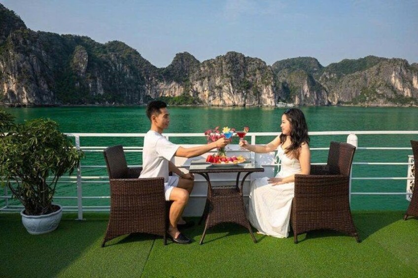 A couple dining at a table with a view of a mountainous coastline. 5